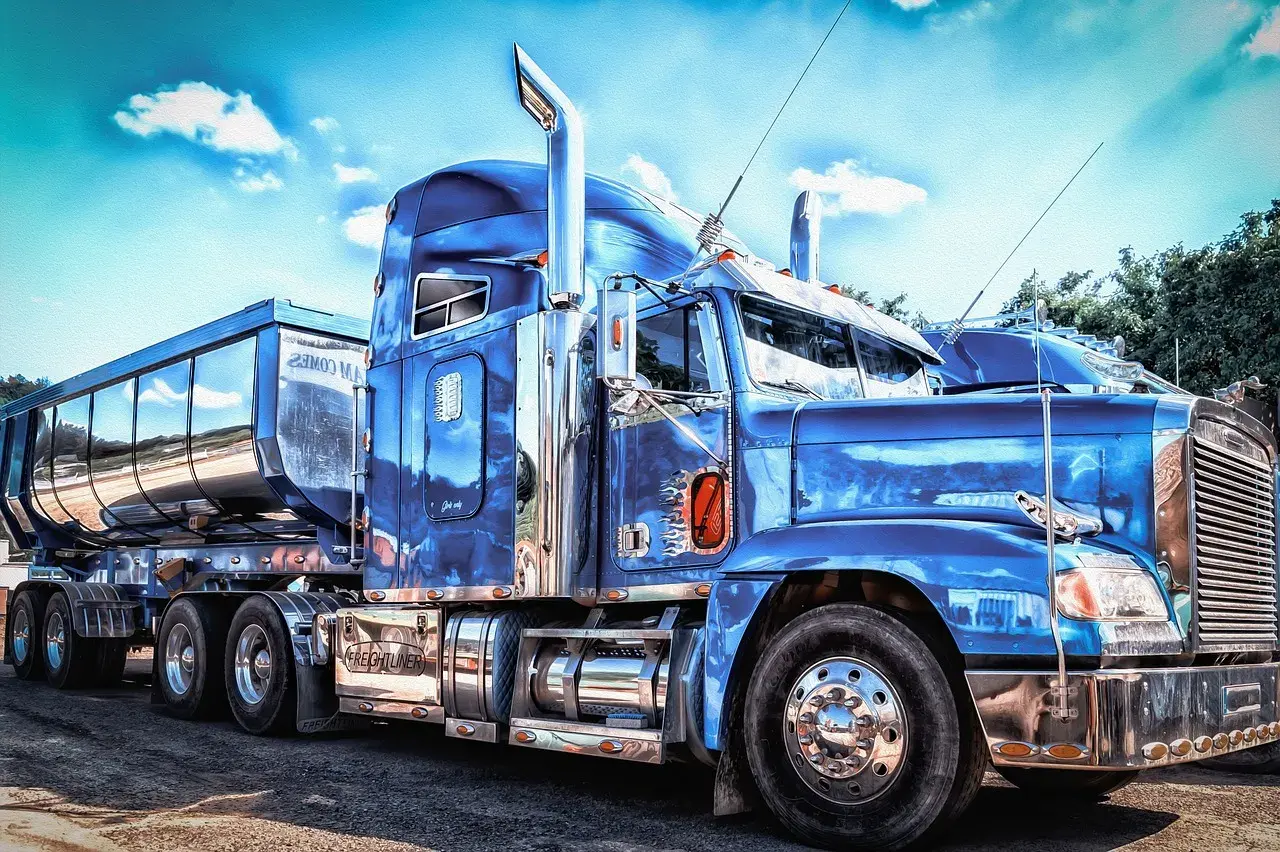 Un camion us bleu étincelant, prêt pour la route. Le chrome brille sous le ciel bleu.