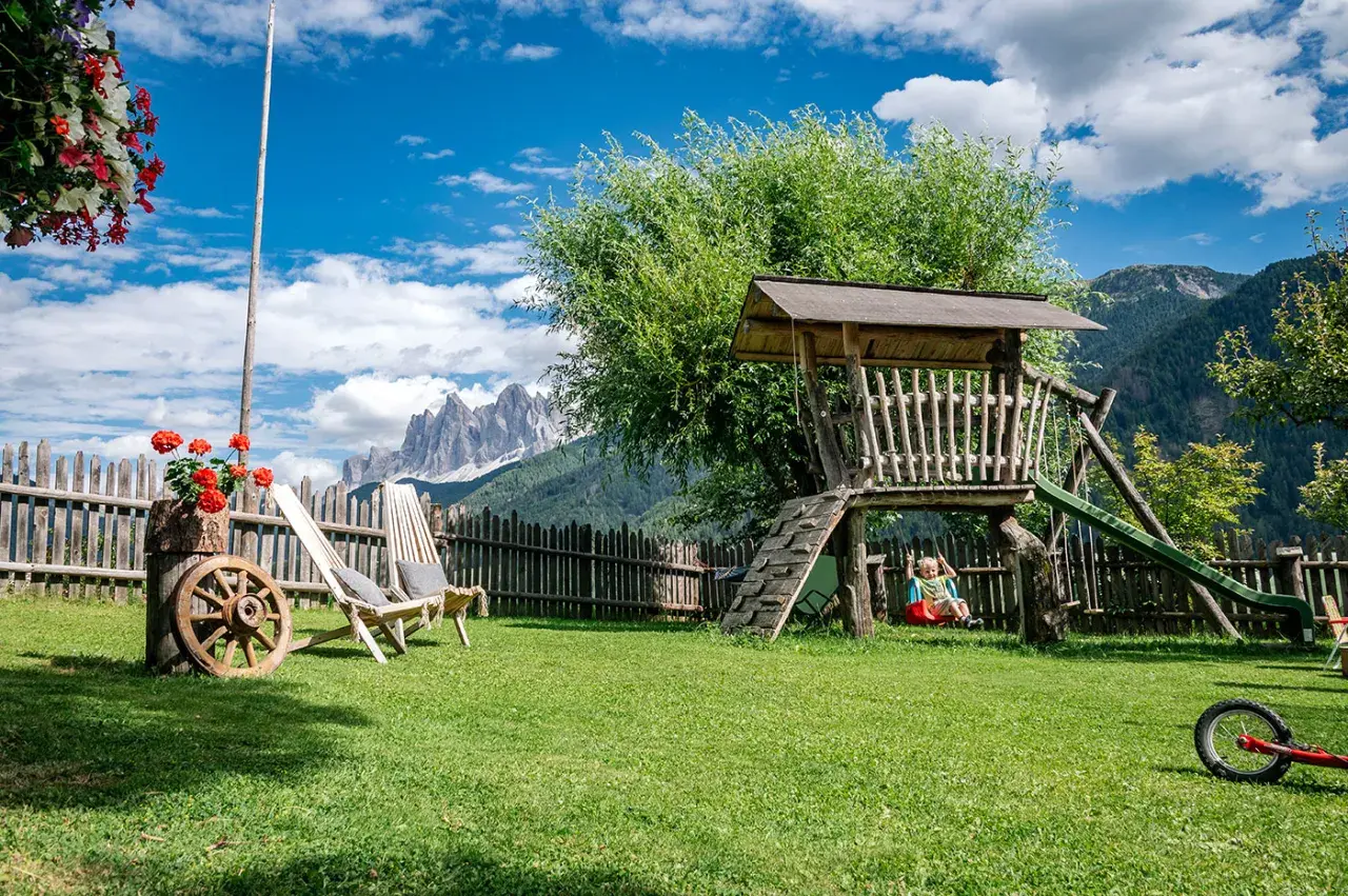Giardino con altalena e montagne sullo sfondo, ideale per agriturismi con gallo rosso.