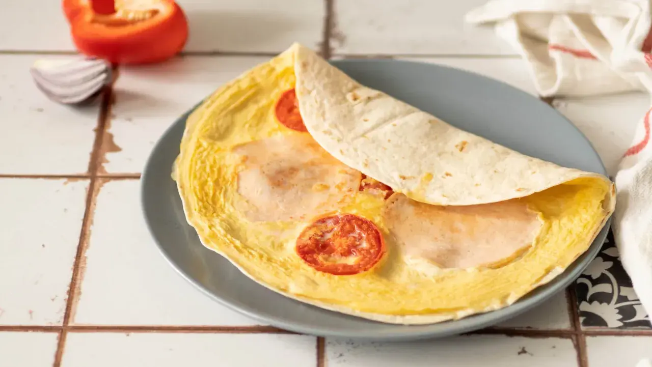 Pyszna tortilla z jajkiem, pomidorem i szynką, gotowa do zjedzenia.