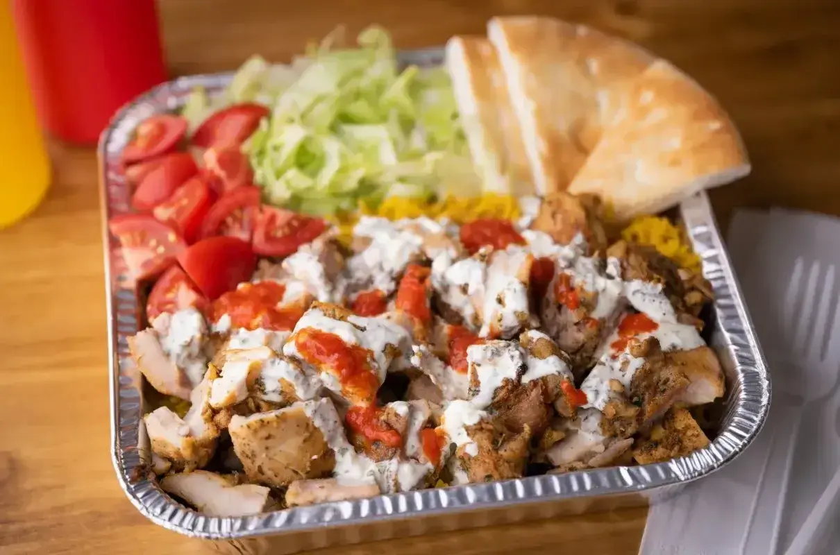 Pyszna shoarma z kurczaka z ryżem, pomidorami, sałatą i chlebkiem pita, polana sosem.