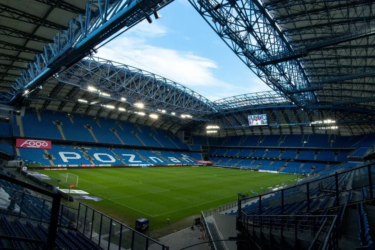 Pusta, błękitna trybuna stadionu Lecha Poznań, gotowa na przyjęcie kibiców. Pojemność stadionu robi wrażenie.