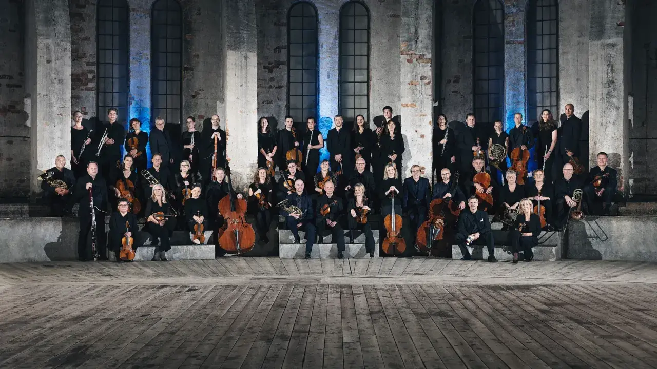 En stor orkester samlad framför Oscars kyrkan, redo att framföra storslagen musik.