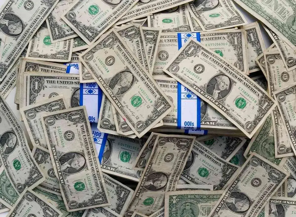 Stosy banknotów jednodolarowych i paczki z napisem "100". To obraz księgowania millenium, gdzie pieniądze odgrywają kluczową rolę.