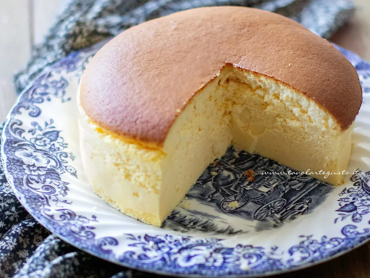 Una soffice torta giapponese, con una fetta mancante, servita su un piatto decorato con un motivo blu e bianco.