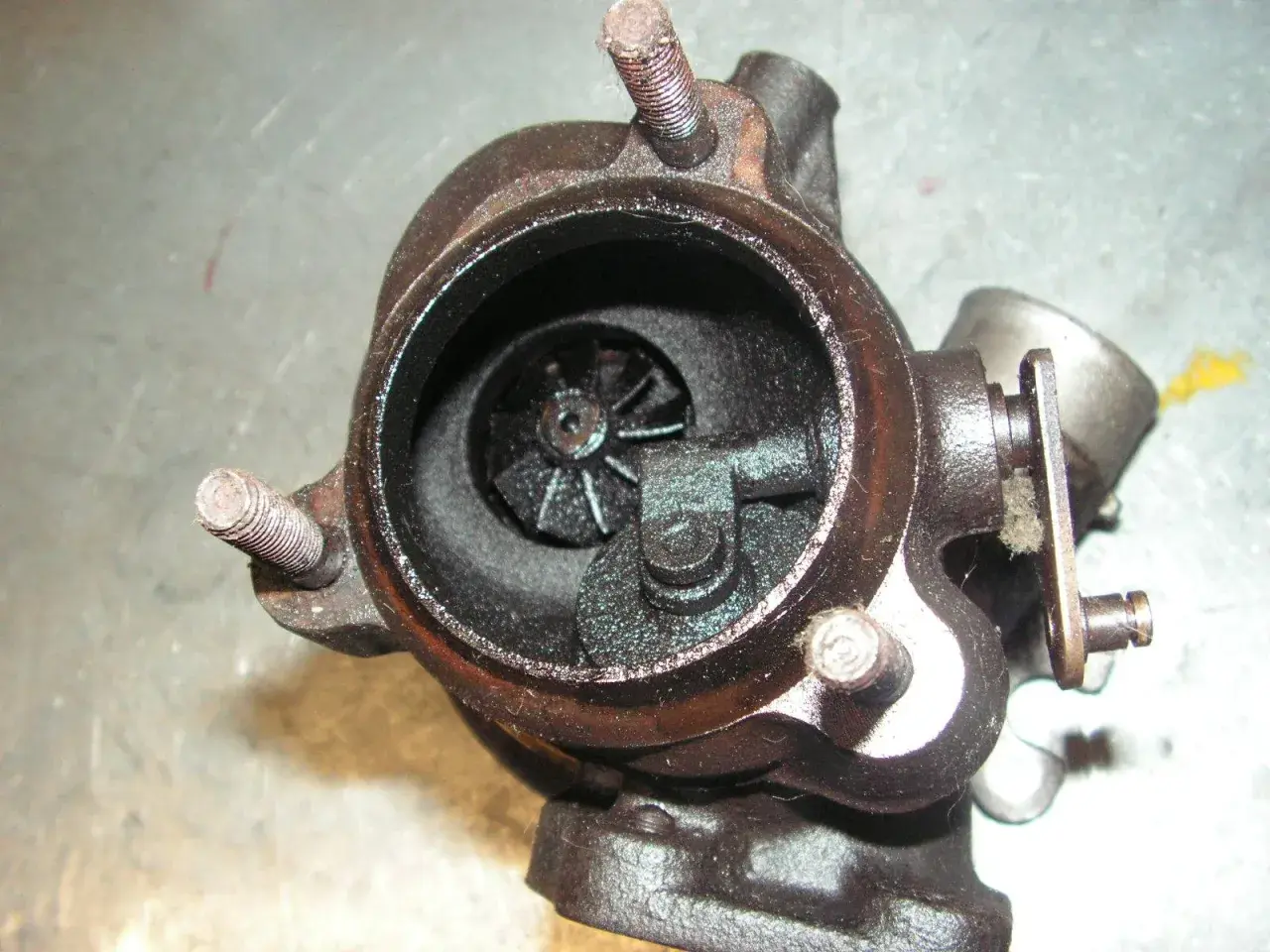 Turbocompresseur usagé, avec une durite turbo percée visible. L'intérieur est encrassé.