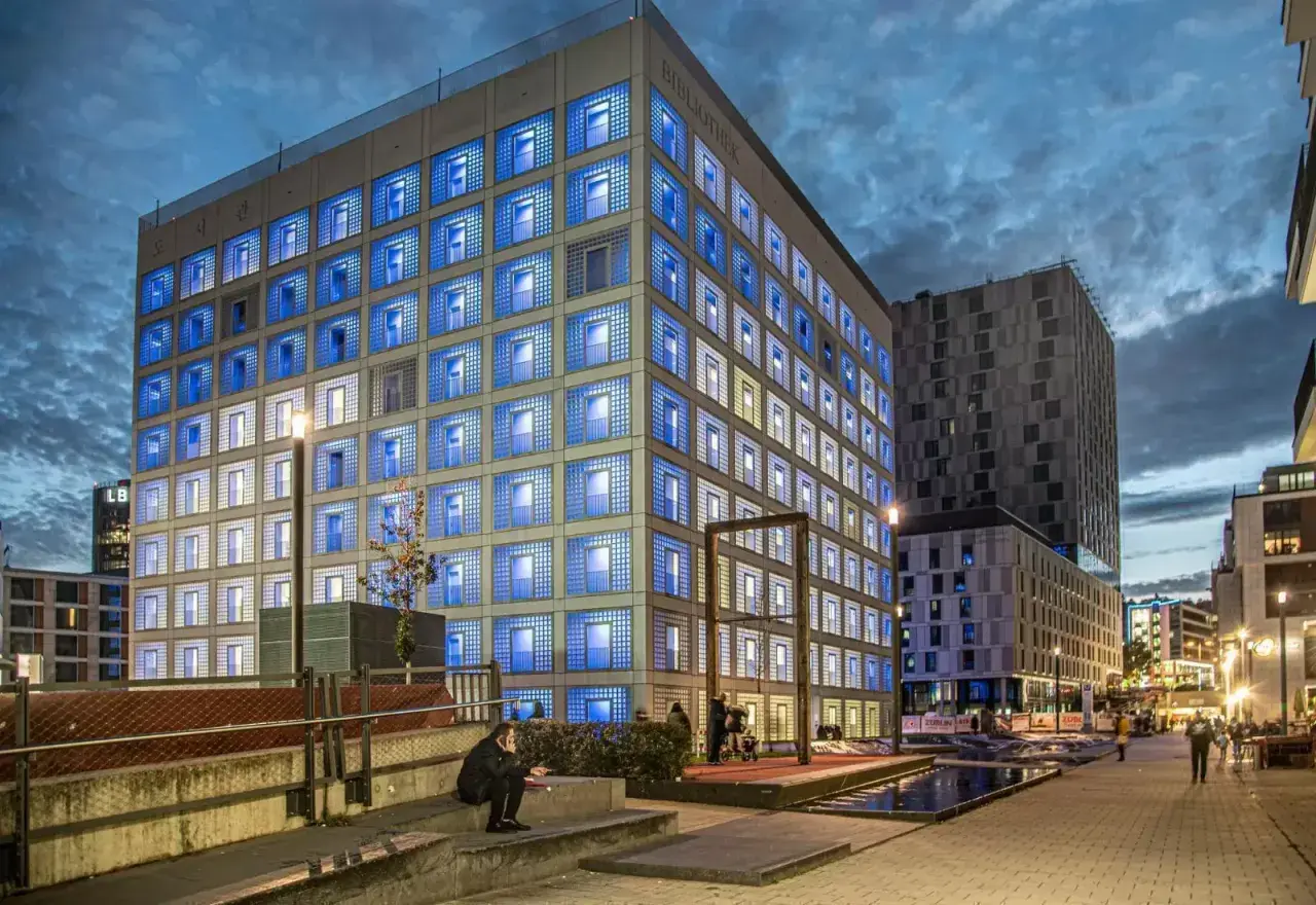 Die Stadtbibliothek Stuttgart leuchtet in der Dämmerung mit blauen Fenstern.