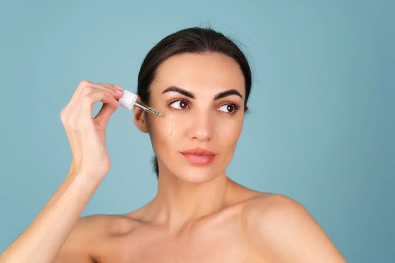 Kvinnan applicerar serum med retinol ansikte.