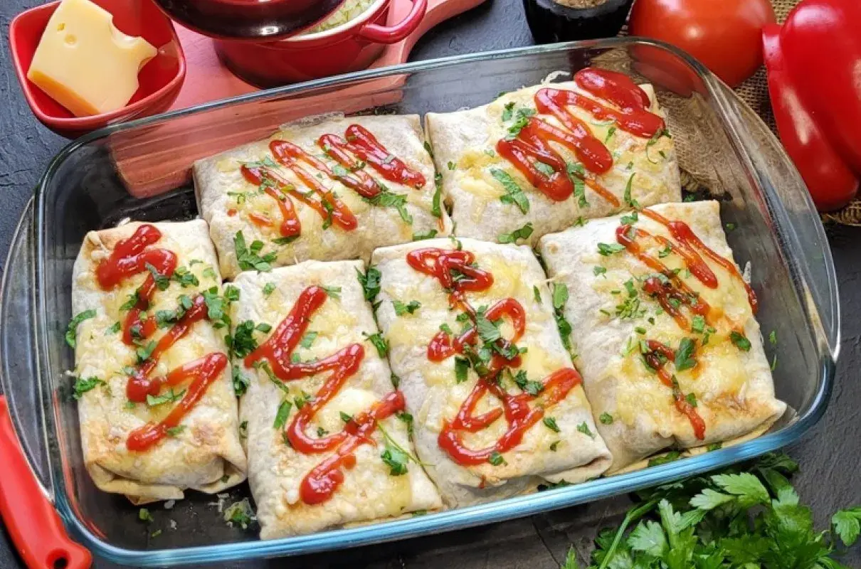 Zapiekana tortilla z mięsem mielonym, serem i ketchupem, posypana natką pietruszki, w szklanym naczyniu.