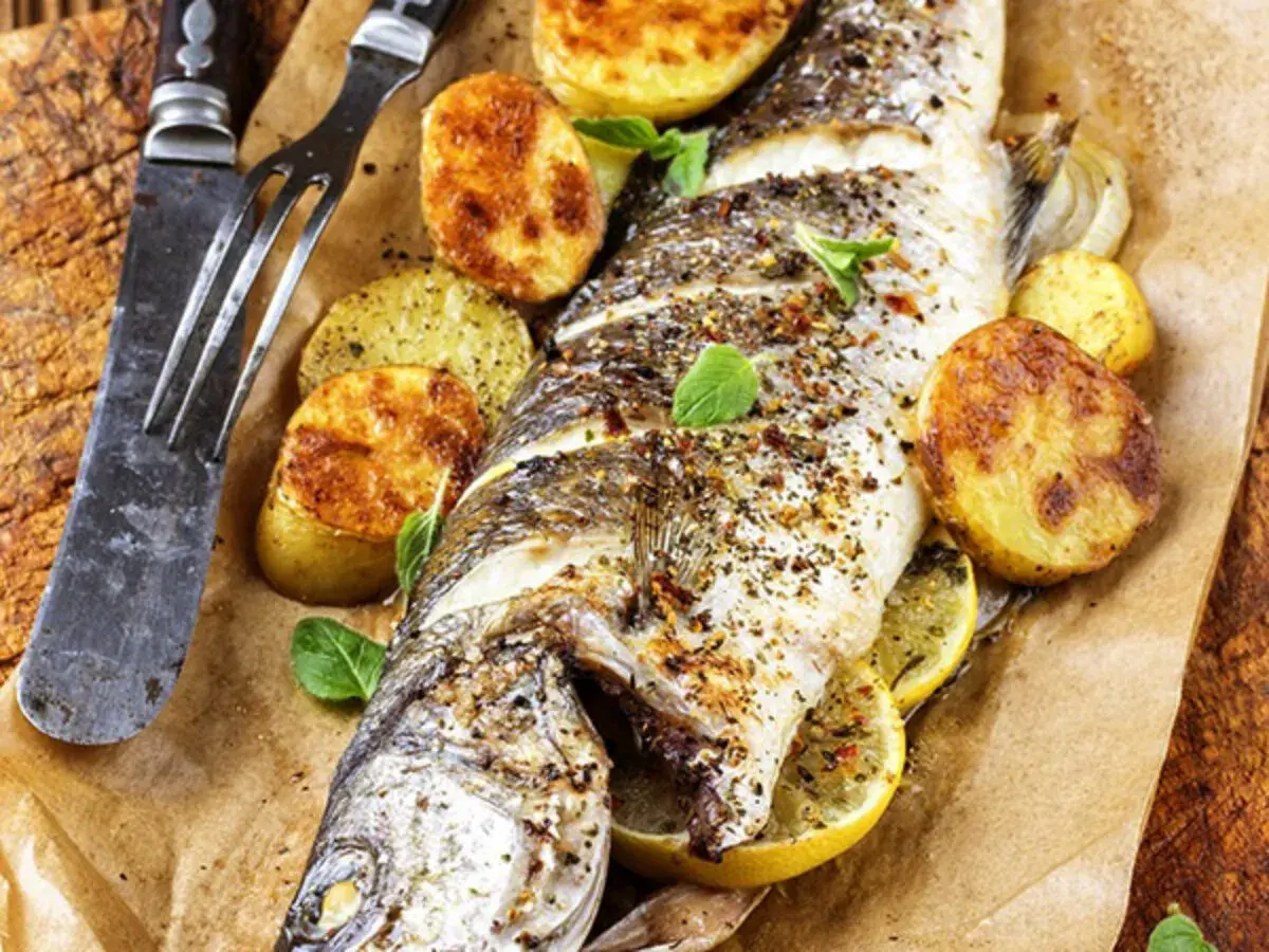 Trota salmonata al forno, dorata e saporita, servita con patate arrosto e limone. Un piatto invitante pronto da gustare.