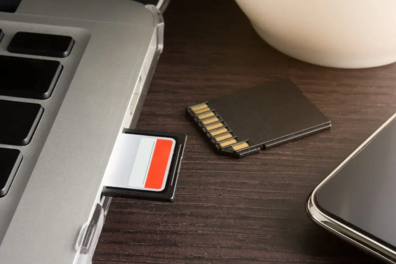 SD-Karte im Laptop-Slot, daneben eine weitere Karte und ein Smartphone. Die SD-Karte im Handy wird nicht erkannt.