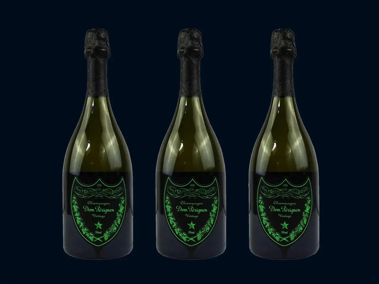 Trzy butelki szampana Dom Pérignon Vintage Brut w ciemnozielonych butelkach z czarnymi kapsułami i zielonymi etykietami.