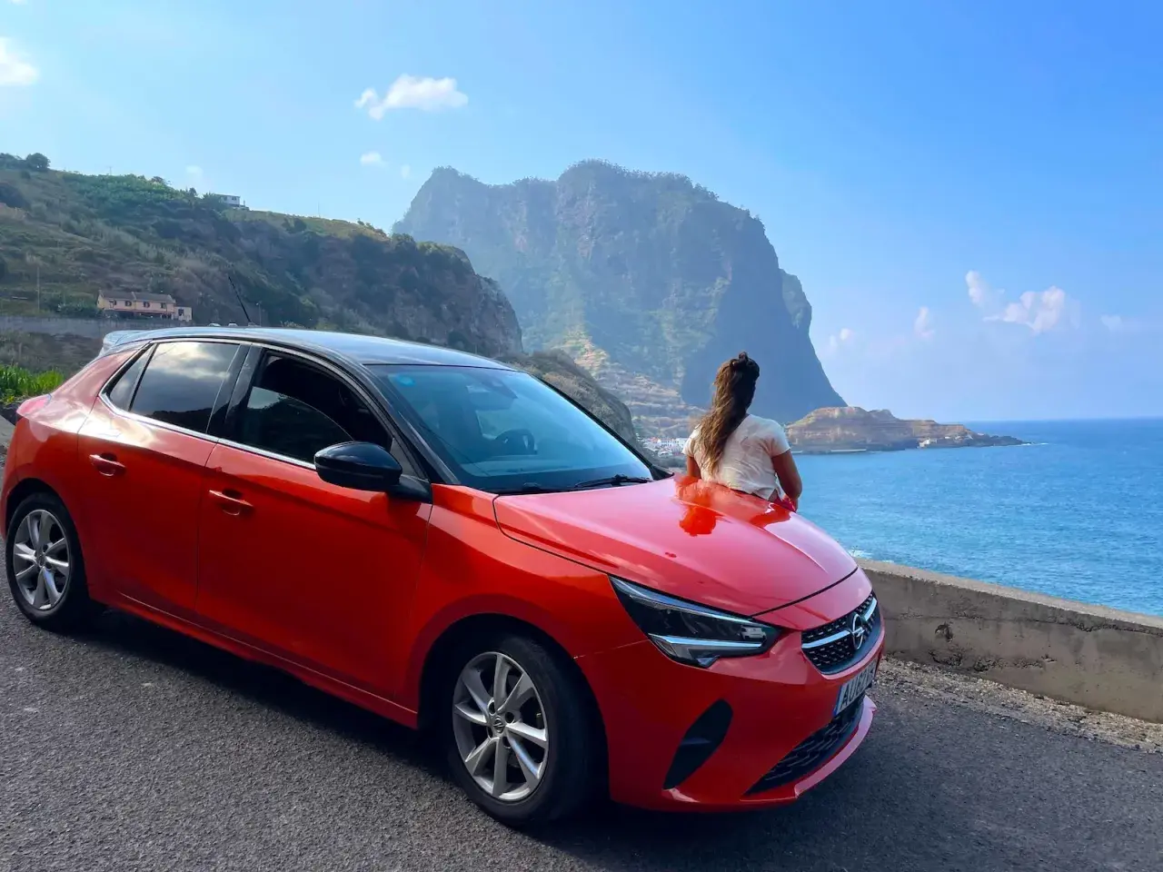 Roter Opel auf Madeira, bereit für eine Fahrt entlang der Küste mit Blick auf die dramatischen Berge und das blaue Meer.