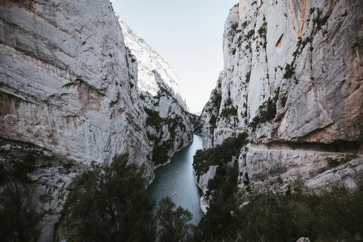El río serpentea entre imponentes paredes rocosas en el congost de Montrebei. Pequeñas embarcaciones navegan tranquilamente por sus aguas.