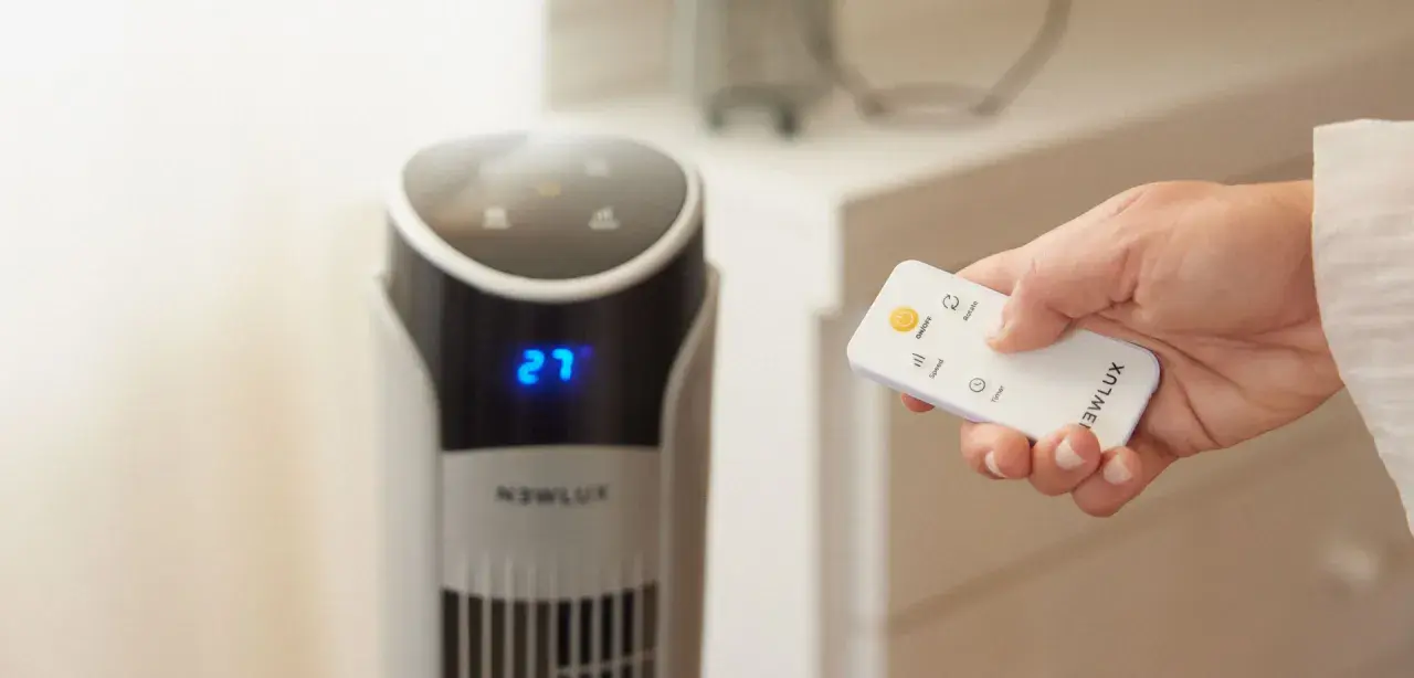 Mano con control remoto ajustando el ventilador para una temperatura ideal para dormir. El display muestra 27 grados.