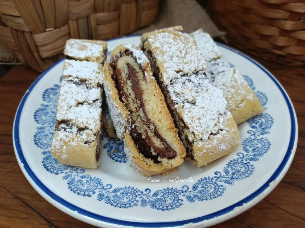 Fette di biscotti della nonna con ripieno di crema al cioccolato, spolverati di zucchero a velo, su un piatto decorato.