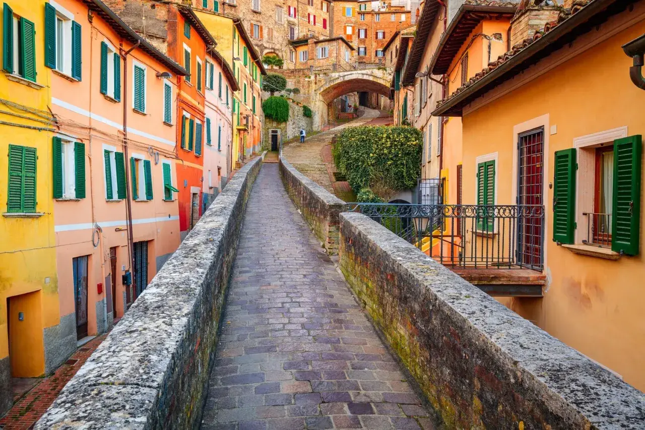 Un vicolo pittoresco a Perugia, con case colorate e un ponte in pietra. Perfetto per scoprire le cose da fare a Perugia.