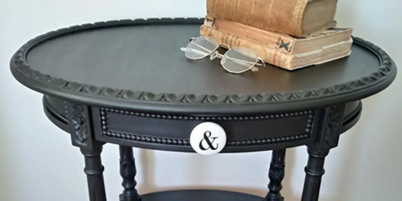 Come trasformare un vecchio comodino in un pezzo d'arredo chic: un tavolino nero con pomello a "&" e libri antichi.