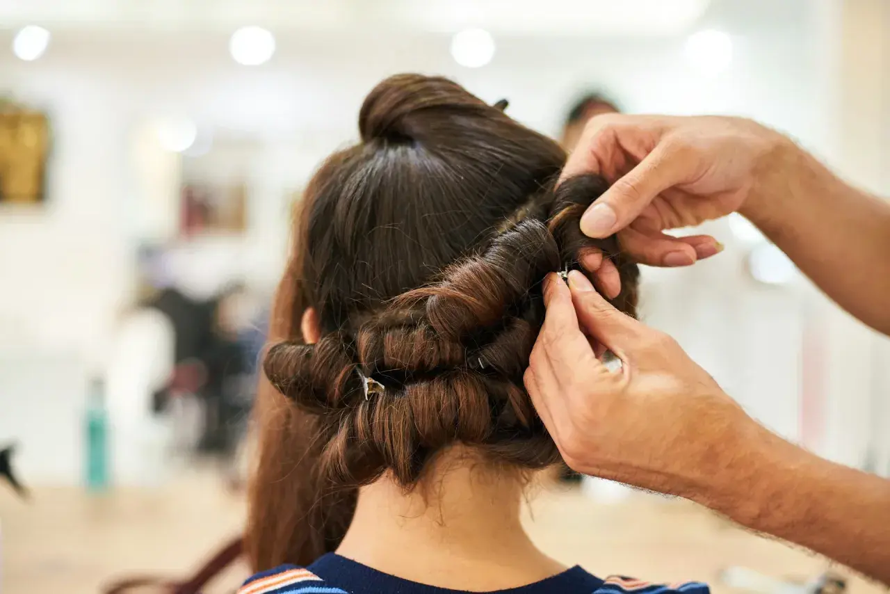Hårstylist hjälper till att rulla håret på spolar för att skapa volym och lockar.