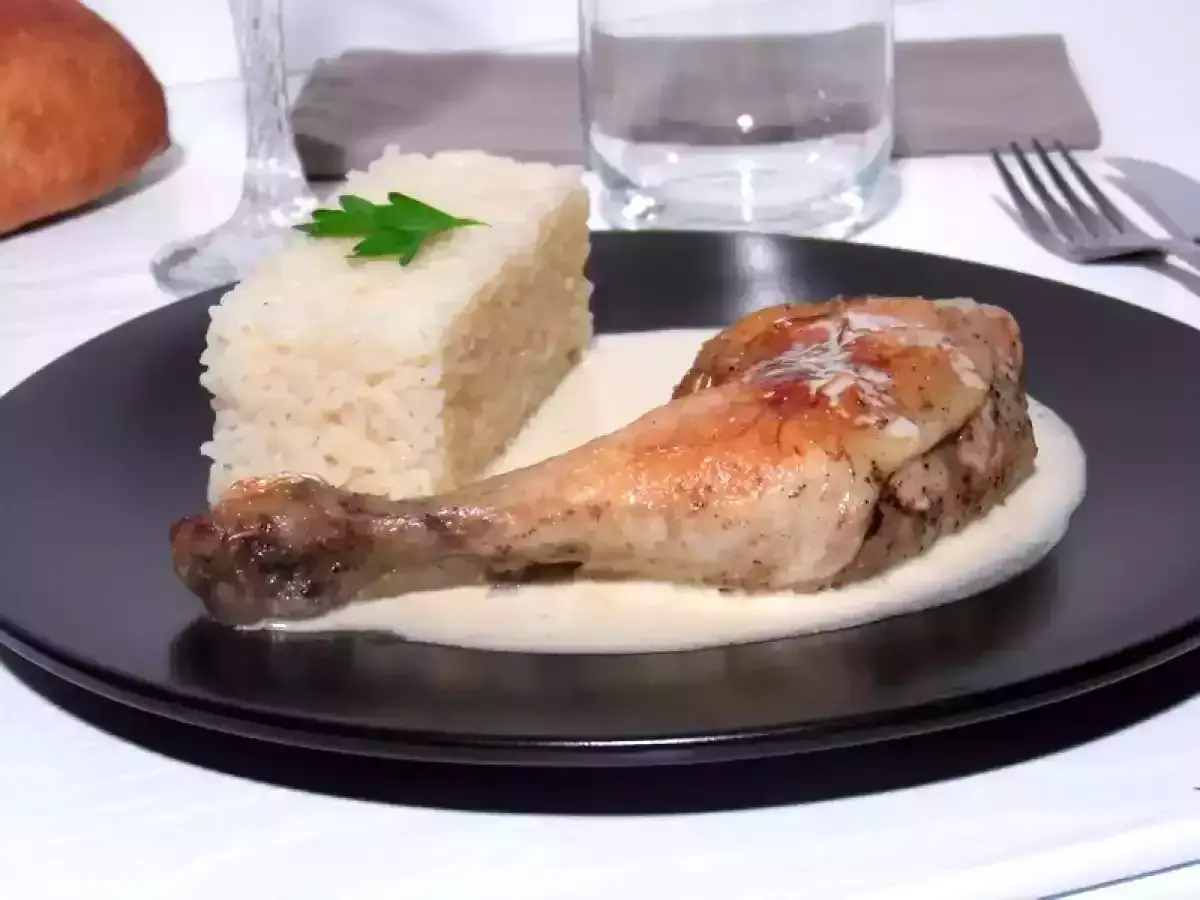 Un délicieux poulet à la crème, servi avec une portion de riz blanc et une feuille de persil. Un plat savoureux et réconfortant.