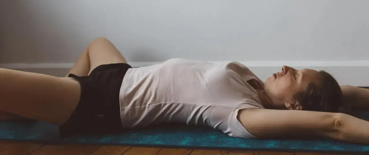 Femme en position de repos, jambes écartées pour un étirement abducteur.