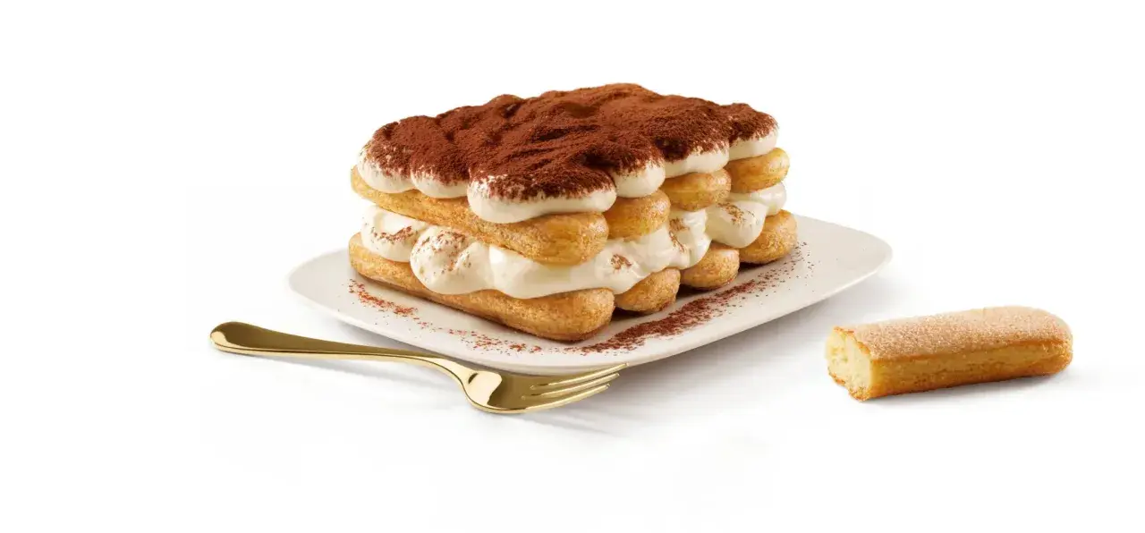 Un tiramisu généreux, fait avec 500g de mascarpone, est prêt à être dégusté. Une cuillère dorée et un biscuit à portée de main.