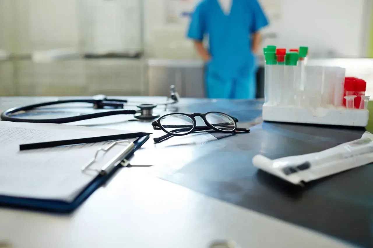 Occhiali, stetoscopio e provette su un tavolo. Il medico di base quanti pazienti ha oggi?
