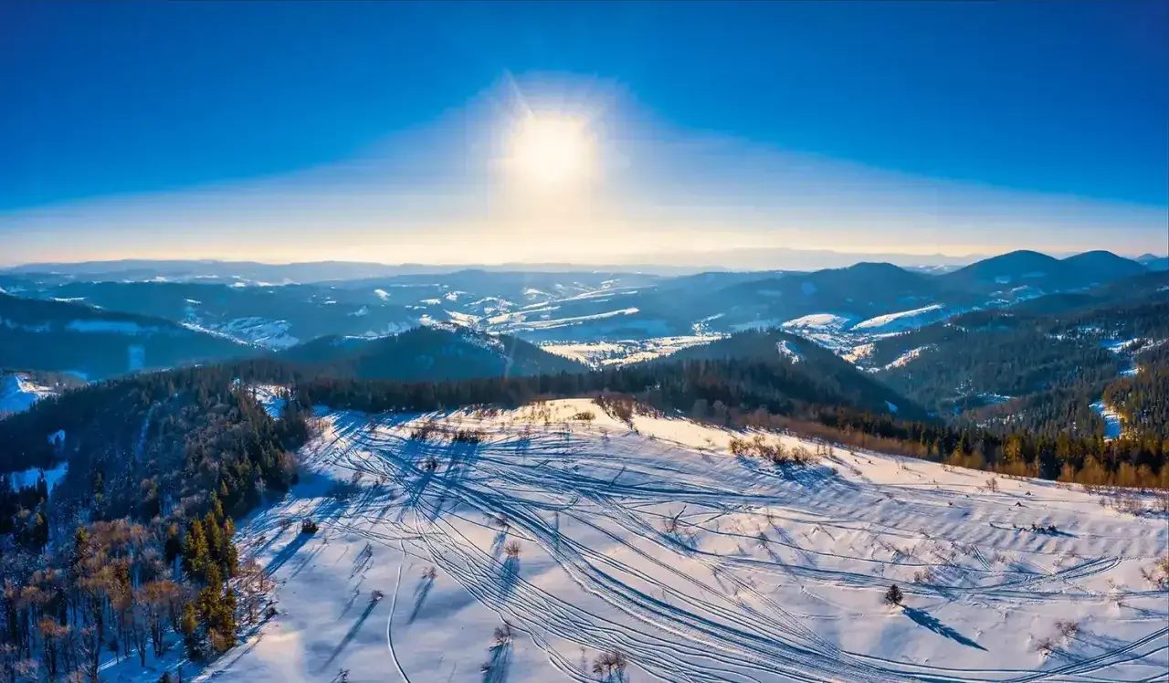 Sonniger Tag im Riesengebirge Skigebiet. Spuren im Schnee zeugen von einem lebhaften Tag auf den Pisten.