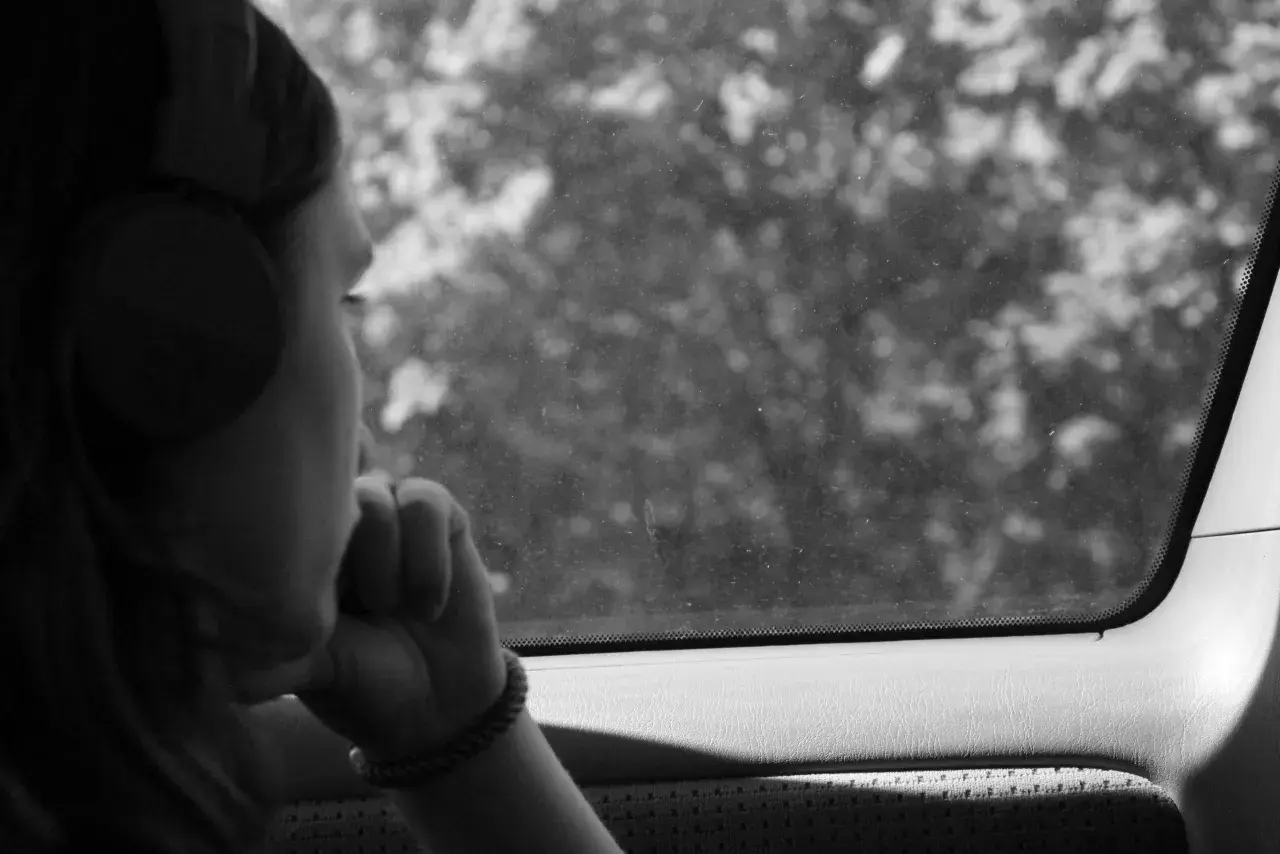 Ragazza con cuffie guarda fuori dal finestrino, persa nei suoi pensieri, come in un loop di depressione, ripetere sempre le stesse cose.
