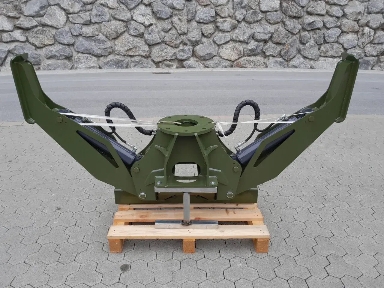 Grüner Forstkran-Greifer mit hydraulischen Armen, bereit für den Einsatz als Forstkran-Abstützung.