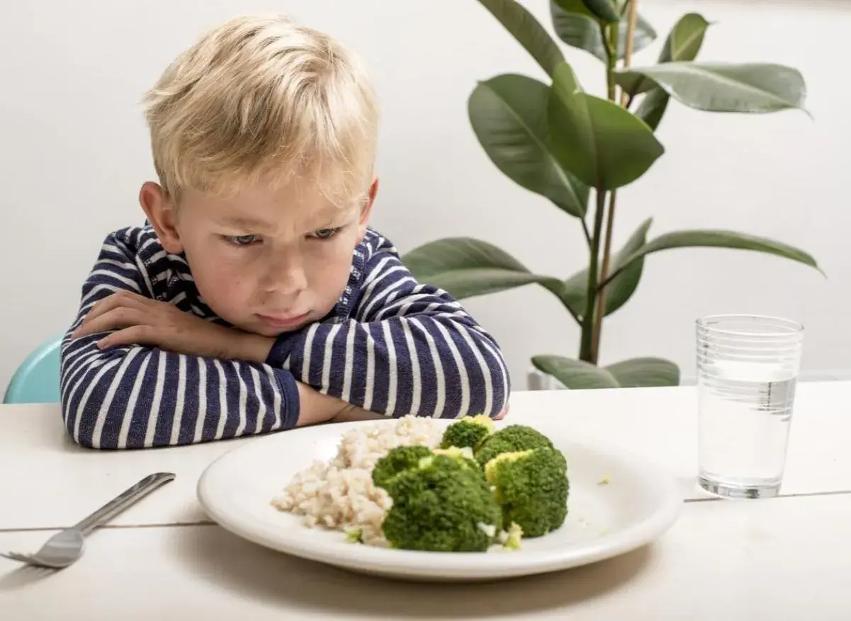 Un enfant boude devant son assiette de riz et brocolis. Une vraie galère pour trouver une idée repas enfant difficile à satisfaire !