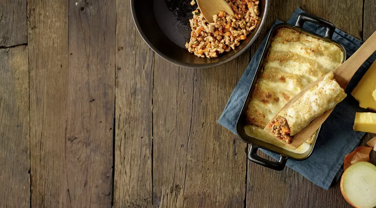 Préparation d'une recette cannelloni viande hachée et béchamel : viande cuisinée dans une poêle, cannelloni garni sur une spatule, plat gratiné au fromage.