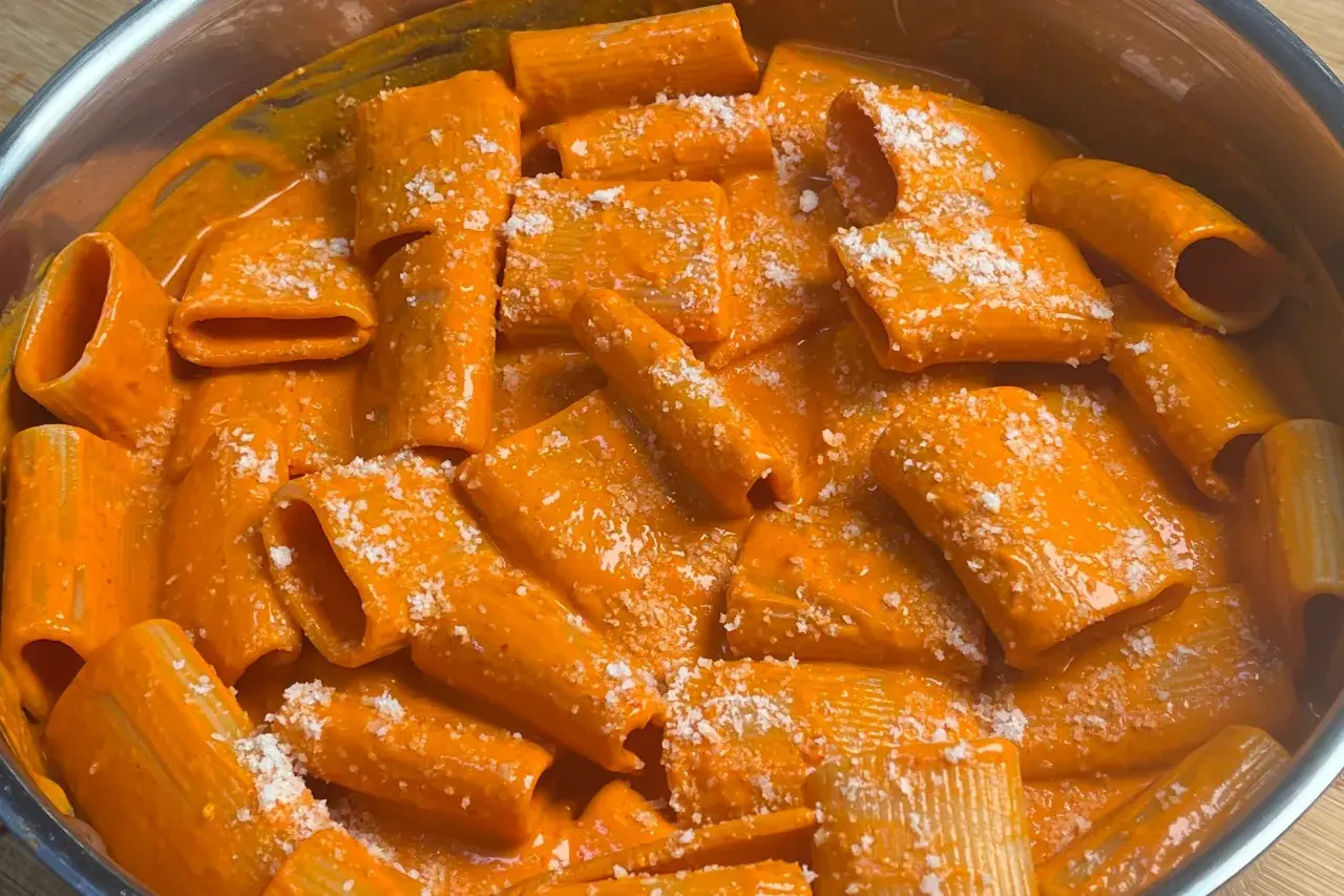 Rigatoni cremosi in salsa all'nduja, cosparsi di formaggio grattugiato. Un piatto invitante e saporito.