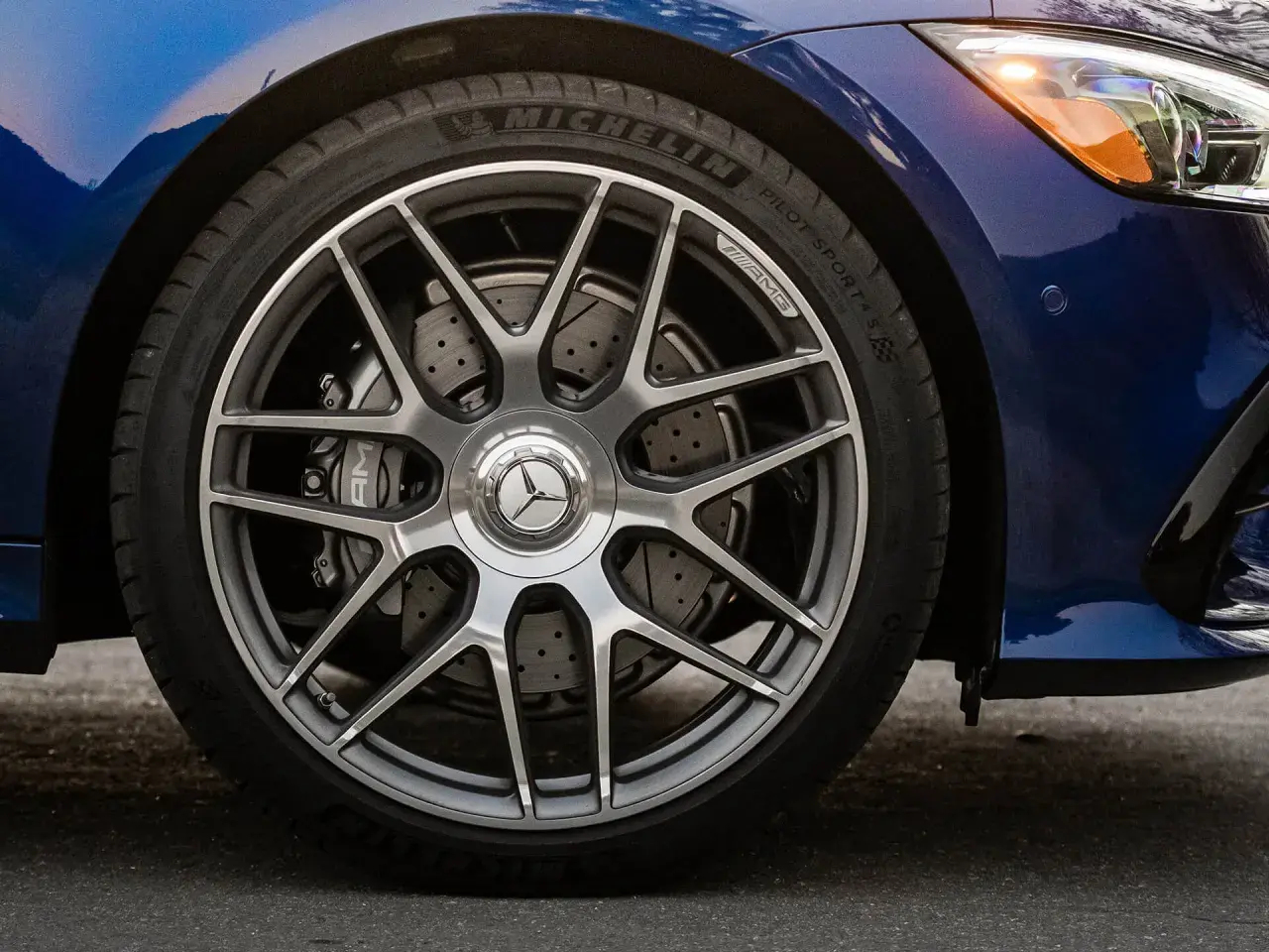 Primo piano della ruota di un'auto blu con cerchi AMG e dischi freno forati, per un controllo freni auto impeccabile.