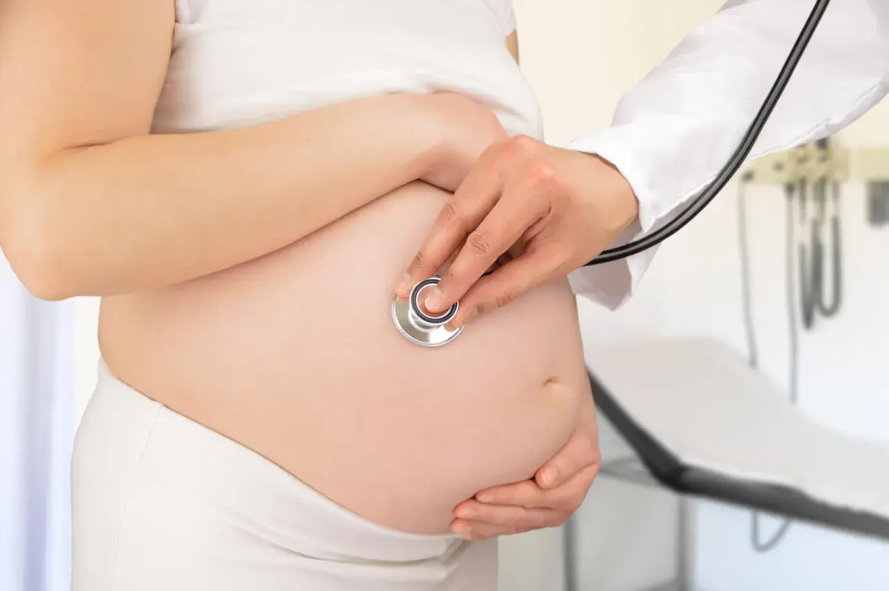 Medico ascolta battito fetale su pancia di donna incinta, controllo per gestosi gravidica.