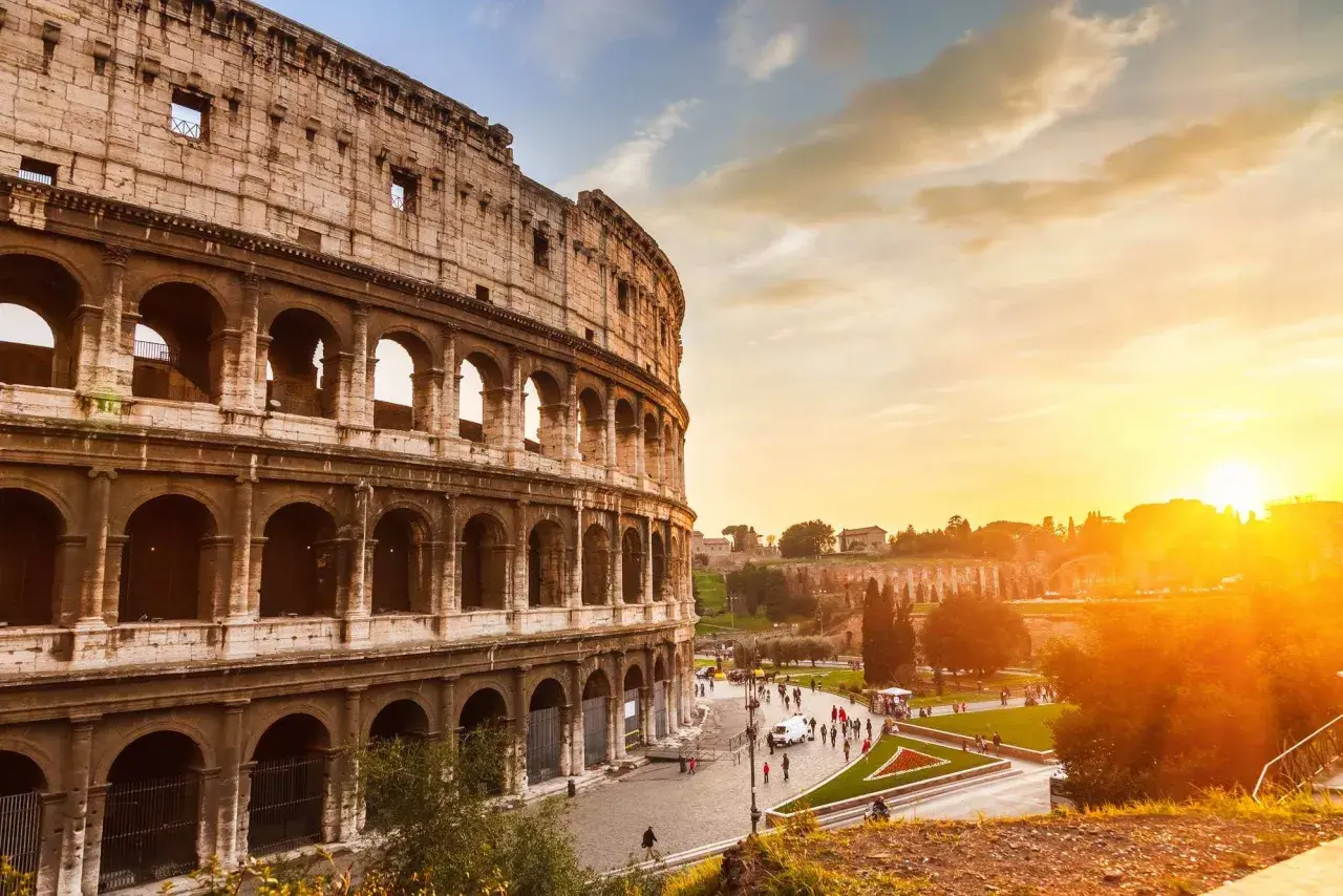 Il Colosseo al tramonto, con il suo clima mite, accoglie visitatori sotto un cielo dorato.