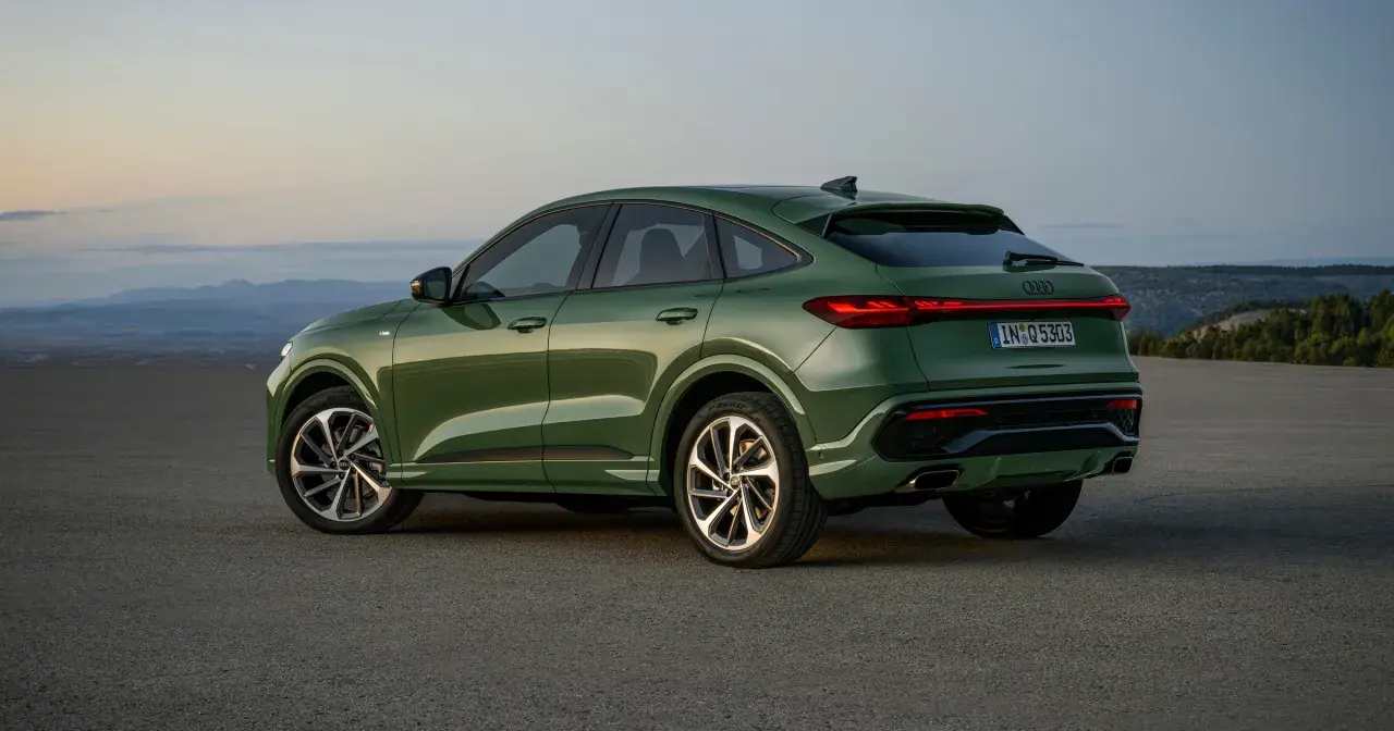 Zielony q5 audi z elegancką linią dachu, zaparkowany na pustkowiu o zachodzie słońca.