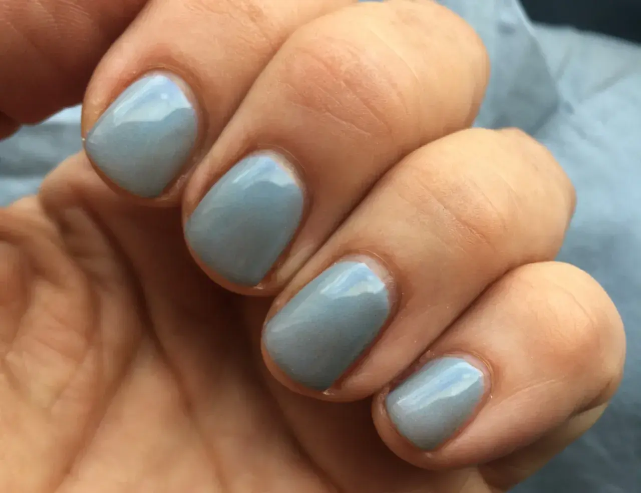 En hand med ljusblå, glansig inglot nagellack.
