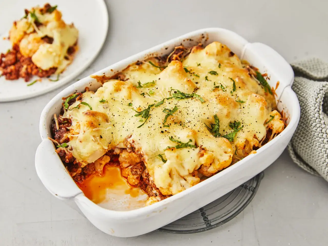 Herzhafter Blumenkohlauflauf mit Hackfleisch, überbacken mit geschmolzenem Käse und garniert mit frischen Kräutern. Ein köstliches Gericht, das Lust auf mehr macht.