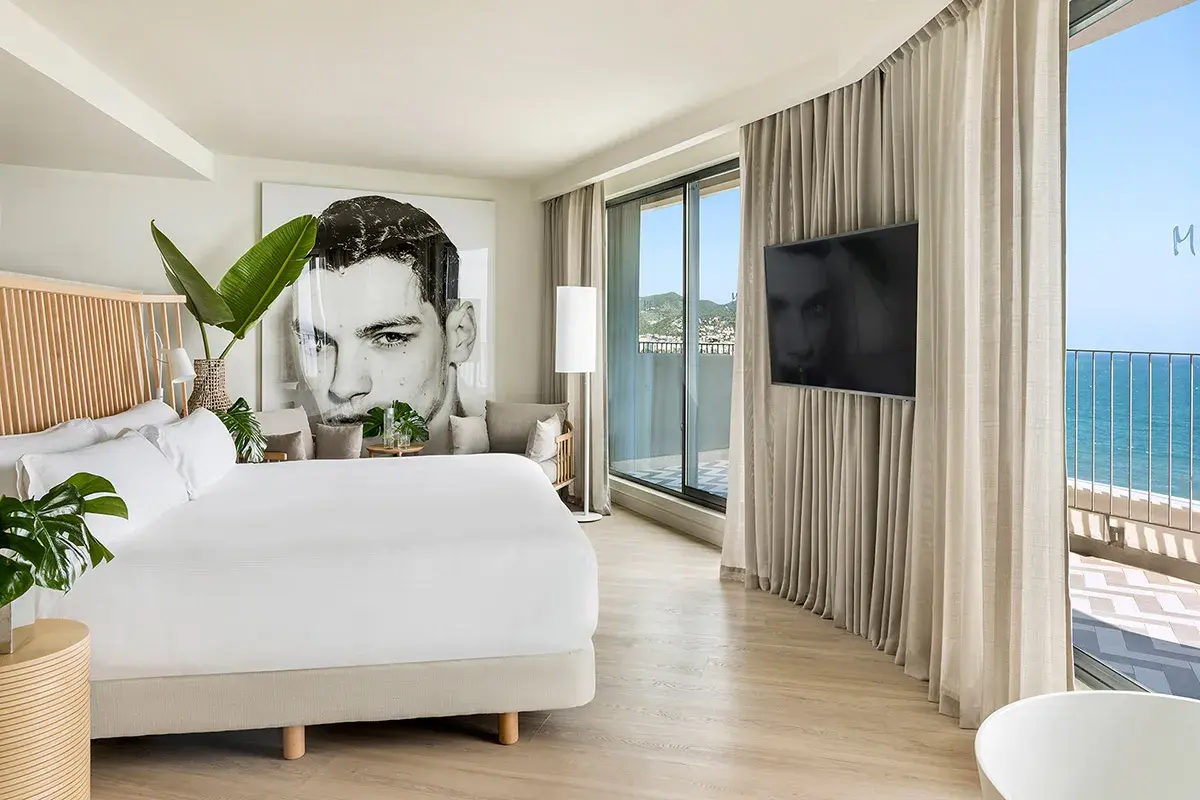 Habitación moderna en el hotel Terramar Sitges con cama king, arte de gran tamaño y vistas al mar.
