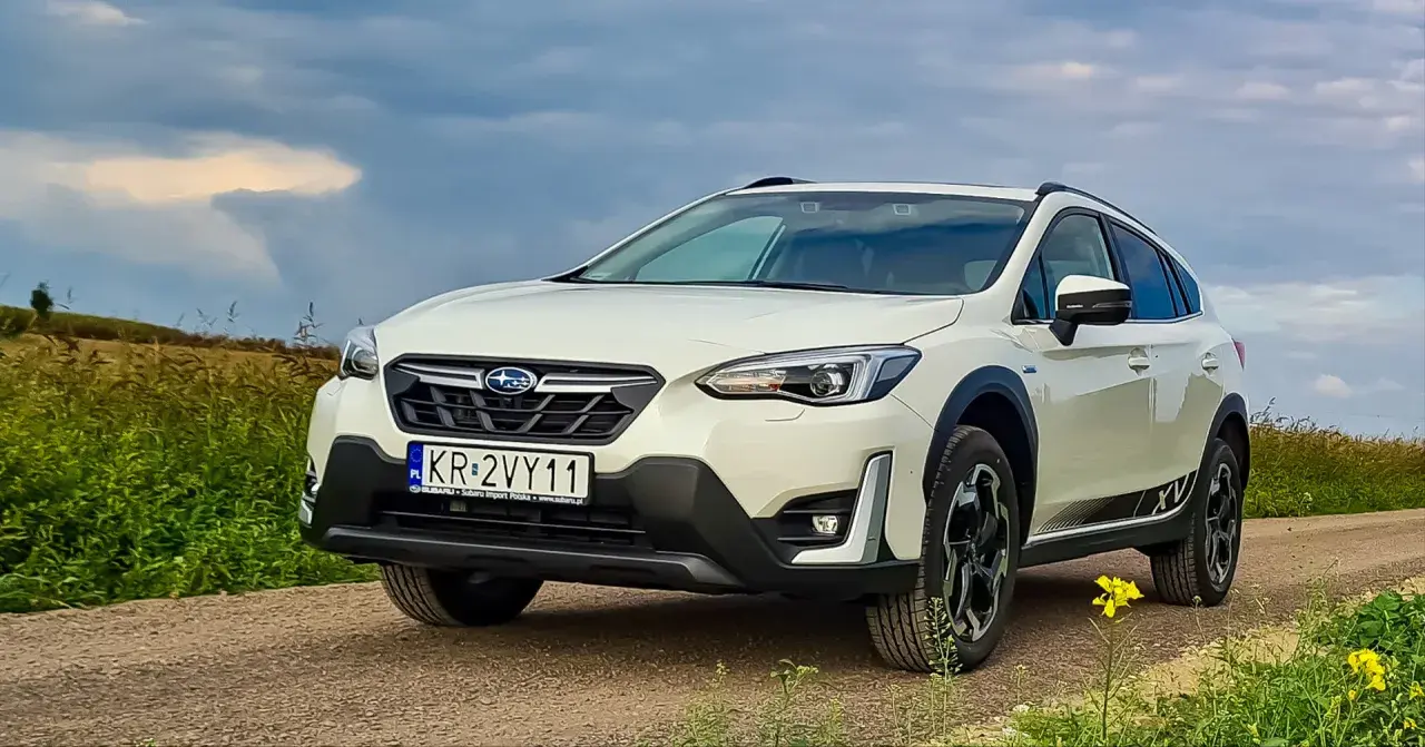 Biały Subaru XV na drodze polnej, z polami w tle. Rozważasz zakup? Sprawdź wady i zalety tego modelu.