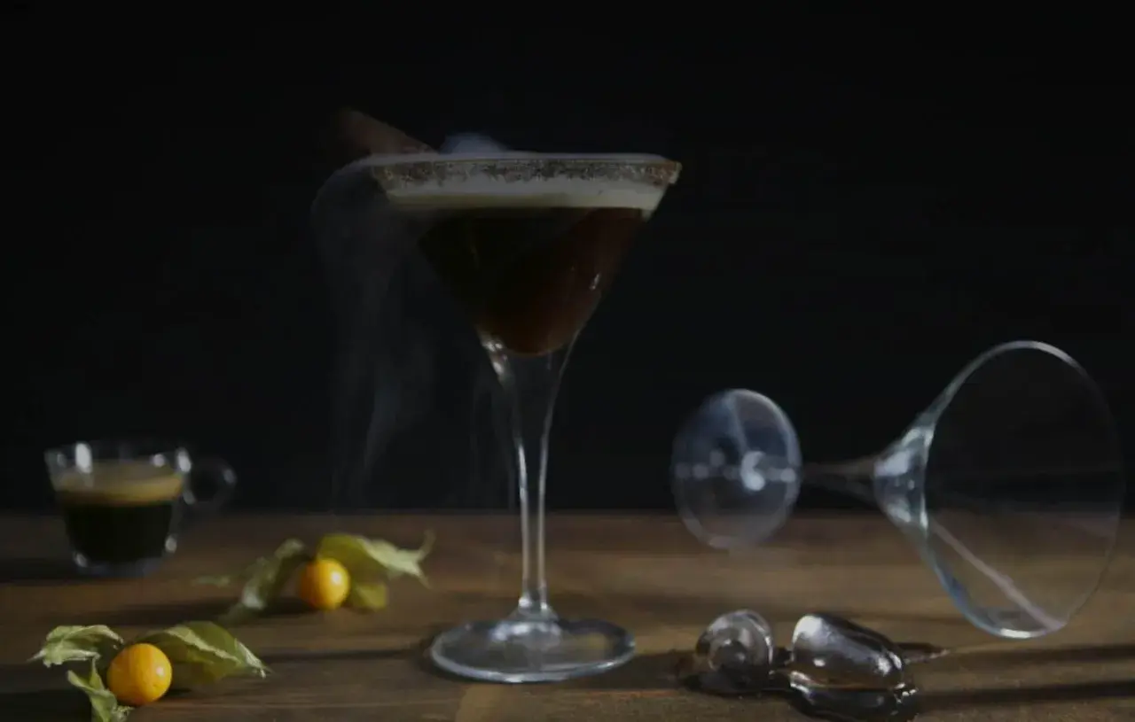 Ein dampfender Espresso Martini mit Zimt und einer kleinen Espressotasse daneben.