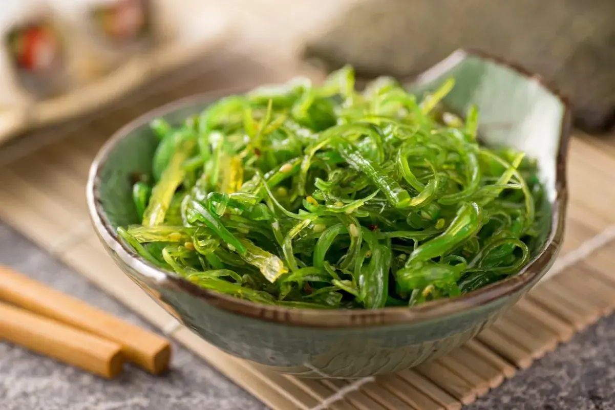 Insalata di alghe wakame in una ciotola, con bacchette. Informazioni su alga wakame controindicazioni.