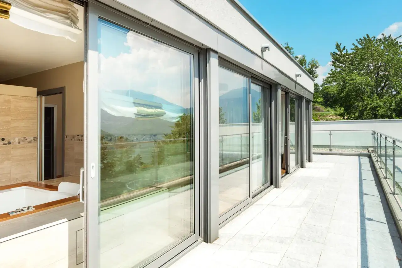 Nowoczesny balkon z przeszklonymi drzwiami i widokiem na góry.