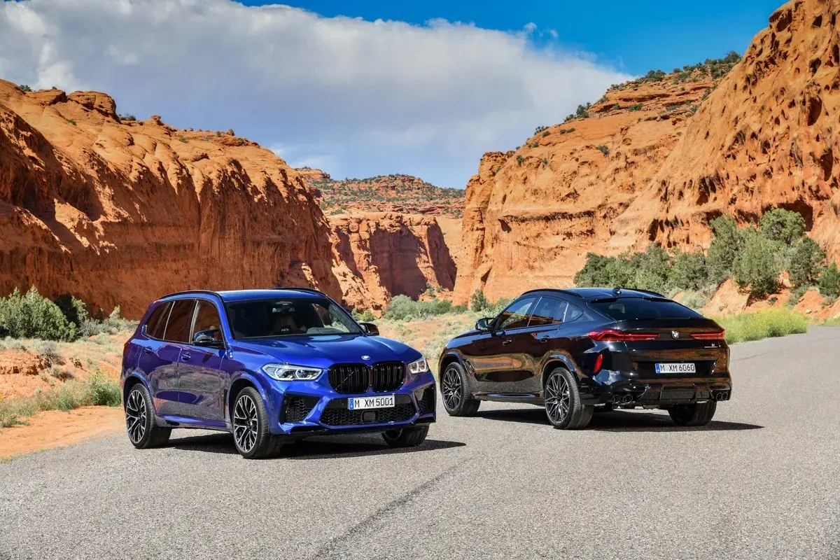 Dwa BMW X5M i X6M w malowniczym kanionie. Jeden niebieski, drugi czarny, gotowe na przygodę.