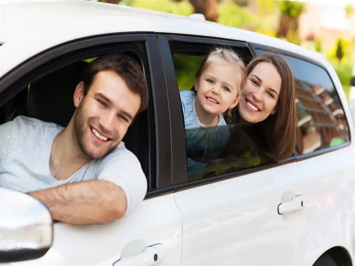 Famiglia sorridente in auto. Pensano al passaggio di proprietà tra familiari costo per un nuovo veicolo.