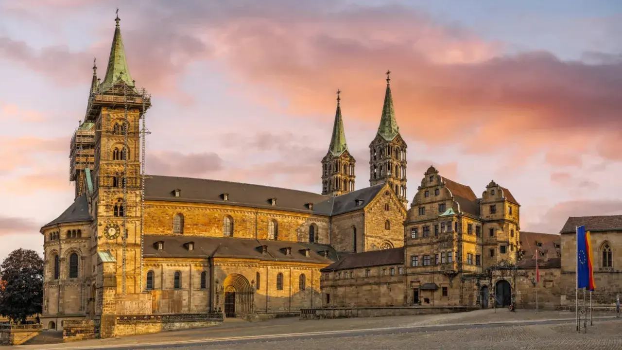 Bamberg Altstadt: Majestätischer Kaiserdom mit Türmen im Abendlicht, umgeben von historischen Gebäuden.