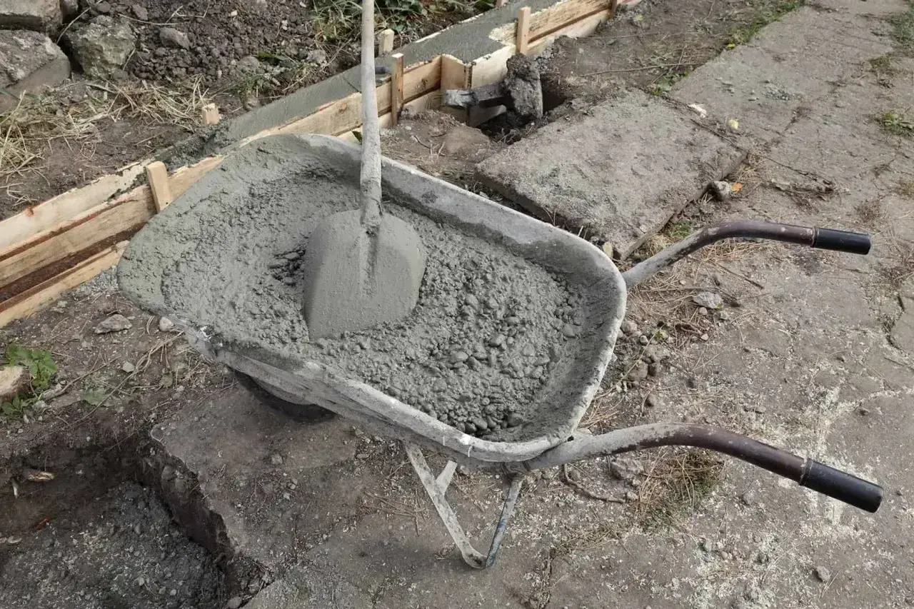 Taczka z betonem i łopatą, gotowa do wylania uziomu fundamentowego.