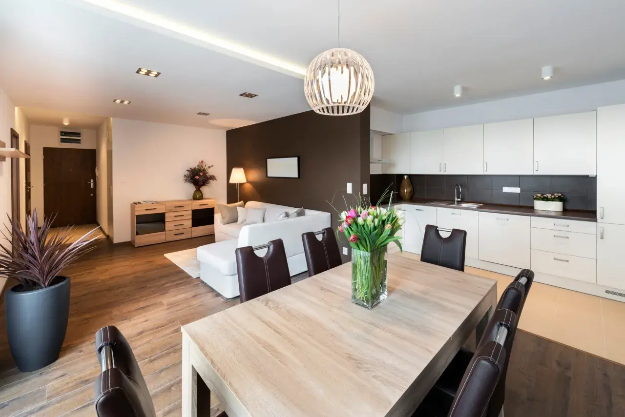 Salon moderne avec cuisine ouverte, table en bois et tulipes. Idéal pour un primo accédant cherchant un espace de vie lumineux et fonctionnel.