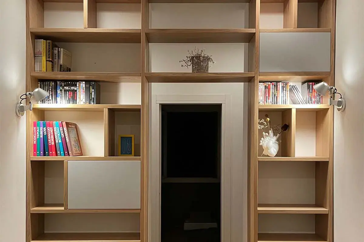 Parete in legno fai da te con libri, DVD e decorazioni. Illuminazione discreta valorizza gli oggetti.