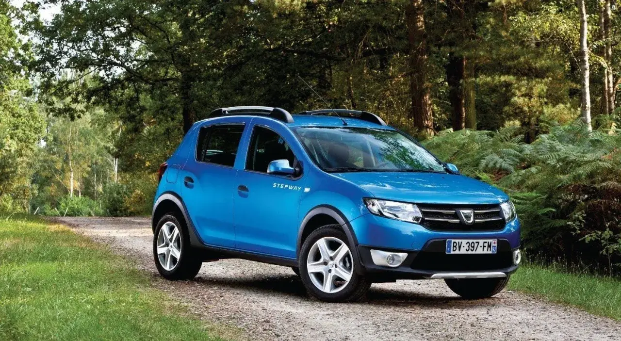 Niebieski Dacia Sandero Stepway na leśnej drodze, gotowy na przygodę.